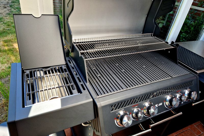 Aufgeklappter Deckel, Grillrost über den Brennern, links der ausgeklappte Seitenkocher mit eigenem Rost