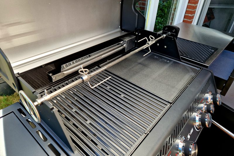 Eingehängter Drehspieß quer über Grillrost und Grillplatte, rechts die Bedienknöpfe